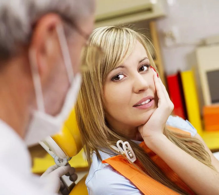 a lady is talking to the dentist and shows him tooth problem